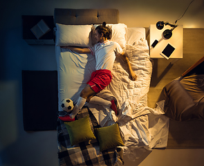 Image showing Top view of young professional football, soccer player sleeping at his bedroom in sportwear with ball