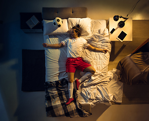 Image showing Top view of young professional football, soccer player sleeping at his bedroom in sportwear with ball