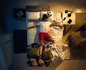 Image showing Top view of young professional football, soccer player sleeping at his bedroom in sportwear with ball