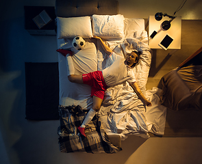 Image showing Top view of young professional football, soccer player sleeping at his bedroom in sportwear with ball