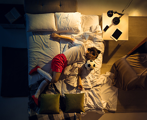 Image showing Top view of young professional football, soccer player sleeping at his bedroom in sportwear with ball