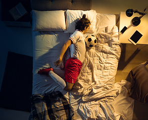 Image showing Top view of young professional football, soccer player sleeping at his bedroom in sportwear with ball