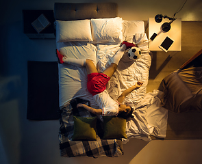 Image showing Top view of young professional football, soccer player sleeping at his bedroom in sportwear with ball