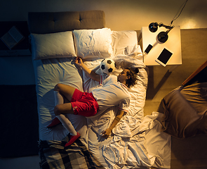 Image showing Top view of young professional football, soccer player sleeping at his bedroom in sportwear with ball