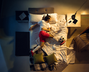 Image showing Top view of young professional football, soccer player sleeping at his bedroom in sportwear with ball