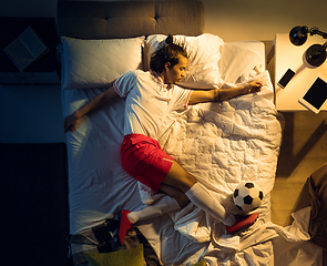 Image showing Top view of young professional football, soccer player sleeping at his bedroom in sportwear with ball