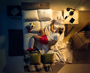 Image showing Top view of young professional football, soccer player sleeping at his bedroom in sportwear with ball