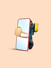 Image showing Handsome delivery man giving order right from smartphone\'s screen, fast delivery concept