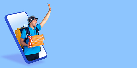 Image showing Handsome delivery man giving order right from smartphone\'s screen, fast delivery concept