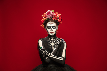 Image showing Young girl in the image of Santa Muerte, Saint death or Sugar skull with bright make-up. Portrait isolated on studio background.