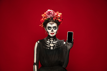 Image showing Young girl in the image of Santa Muerte, Saint death or Sugar skull with bright make-up. Portrait isolated on studio background.