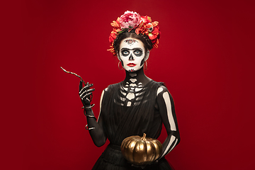 Image showing Young girl in the image of Santa Muerte, Saint death or Sugar skull with bright make-up. Portrait isolated on studio background.