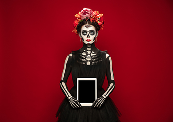 Image showing Young girl in the image of Santa Muerte, Saint death or Sugar skull with bright make-up. Portrait isolated on studio background.