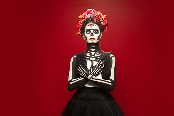 Image showing Young girl in the image of Santa Muerte, Saint death or Sugar skull with bright make-up. Portrait isolated on studio background.