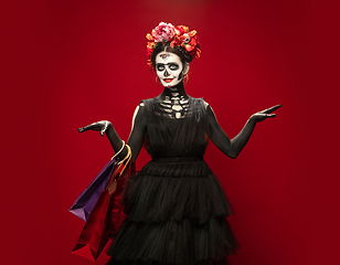 Image showing Young girl in the image of Santa Muerte, Saint death or Sugar skull with bright make-up. Portrait isolated on studio background.