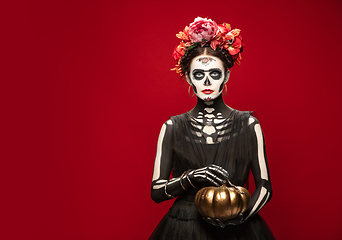 Image showing Young girl in the image of Santa Muerte, Saint death or Sugar skull with bright make-up. Portrait isolated on studio background.