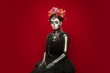 Image showing Young girl in the image of Santa Muerte, Saint death or Sugar skull with bright make-up. Portrait isolated on studio background.