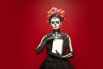 Image showing Young girl in the image of Santa Muerte, Saint death or Sugar skull with bright make-up. Portrait isolated on studio background.