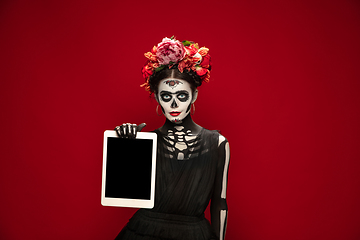 Image showing Young girl in the image of Santa Muerte, Saint death or Sugar skull with bright make-up. Portrait isolated on studio background.