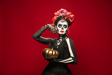 Image showing Young girl in the image of Santa Muerte, Saint death or Sugar skull with bright make-up. Portrait isolated on studio background.