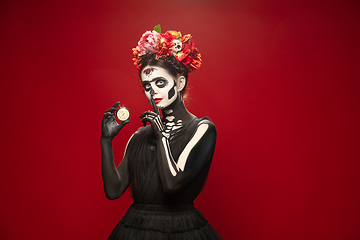 Image showing Young girl in the image of Santa Muerte, Saint death or Sugar skull with bright make-up. Portrait isolated on studio background.