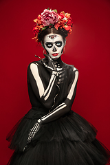 Image showing Young girl in the image of Santa Muerte, Saint death or Sugar skull with bright make-up. Portrait isolated on studio background.