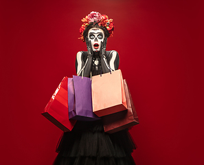 Image showing Young girl in the image of Santa Muerte, Saint death or Sugar skull with bright make-up. Portrait isolated on studio background.