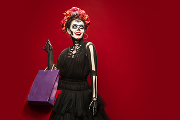 Image showing Young girl in the image of Santa Muerte, Saint death or Sugar skull with bright make-up. Portrait isolated on studio background.