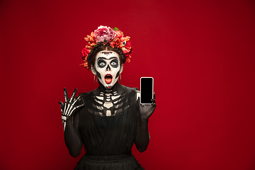 Image showing Young girl in the image of Santa Muerte, Saint death or Sugar skull with bright make-up. Portrait isolated on studio background.