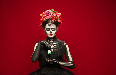 Image showing Young girl in the image of Santa Muerte, Saint death or Sugar skull with bright make-up. Portrait isolated on studio background.