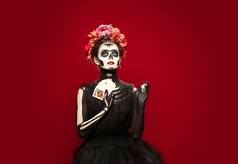 Image showing Young girl in the image of Santa Muerte, Saint death or Sugar skull with bright make-up. Portrait isolated on studio background.