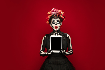 Image showing Young girl in the image of Santa Muerte, Saint death or Sugar skull with bright make-up. Portrait isolated on studio background.