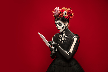 Image showing Young girl in the image of Santa Muerte, Saint death or Sugar skull with bright make-up. Portrait isolated on studio background.