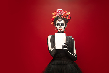 Image showing Young girl in the image of Santa Muerte, Saint death or Sugar skull with bright make-up. Portrait isolated on studio background.