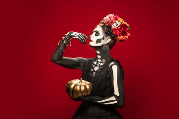 Image showing Young girl in the image of Santa Muerte, Saint death or Sugar skull with bright make-up. Portrait isolated on studio background.