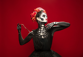 Image showing Young girl in the image of Santa Muerte, Saint death or Sugar skull with bright make-up. Portrait isolated on studio background.