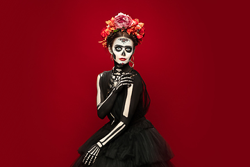 Image showing Young girl in the image of Santa Muerte, Saint death or Sugar skull with bright make-up. Portrait isolated on studio background.