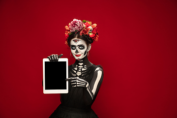 Image showing Young girl in the image of Santa Muerte, Saint death or Sugar skull with bright make-up. Portrait isolated on studio background.