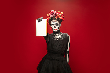 Image showing Young girl in the image of Santa Muerte, Saint death or Sugar skull with bright make-up. Portrait isolated on studio background.