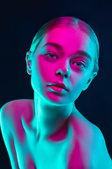 Image showing Portrait of female fashion model in neon light on dark studio background.