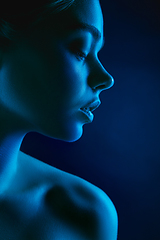 Image showing Portrait of female fashion model in neon light on dark studio background.