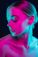 Image showing Portrait of female fashion model in neon light on dark studio background.