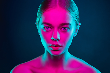 Image showing Portrait of female fashion model in neon light on dark studio background.