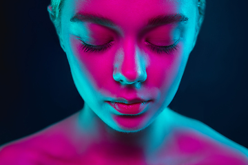 Image showing Portrait of female fashion model in neon light on dark studio background.