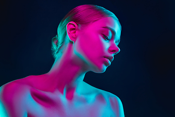 Image showing Portrait of female fashion model in neon light on dark studio background.