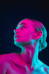 Image showing Portrait of female fashion model in neon light on dark studio background.