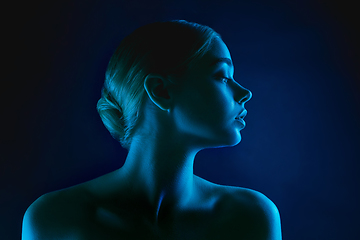 Image showing Portrait of female fashion model in neon light on dark studio background.