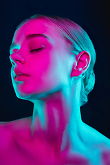 Image showing Portrait of female fashion model in neon light on dark studio background.