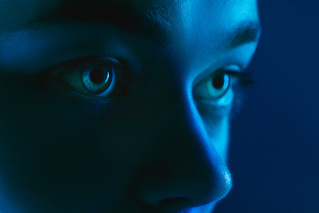 Image showing Portrait of female fashion model in neon light on dark studio background.