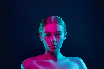 Image showing Portrait of female fashion model in neon light on dark studio background.